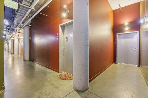 A hallway with a rug on the floor and doors on both sides.