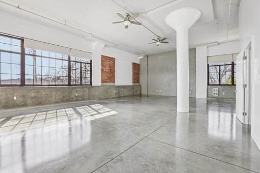 A large empty room with a fan and a window.