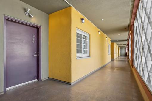 A long hallway with a purple door on the left and a yellow door on the right.