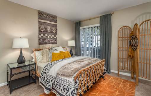 A bedroom with a bed, nightstand, and window.