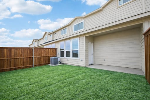 A house with a brown fence and a green lawn.
