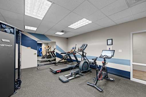 A gym with a Nautilus machine, a treadmill, a stationary bike, and a weight bench.