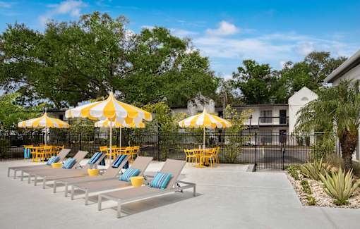 A sunny day at the pool with yellow umbrellas and lounge chairs.