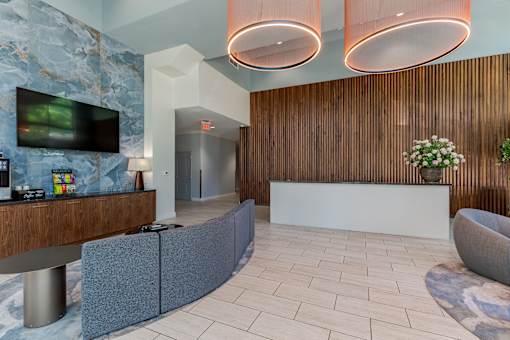 A reception area with a white reception desk and a TV mounted on the wall.