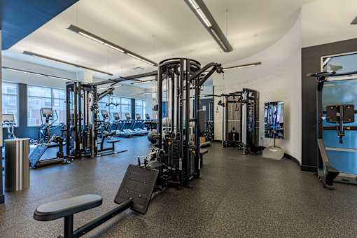 A gym with a variety of equipment including treadmills, weights, and exercise machines.