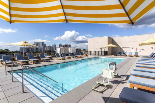 Pool sun deck with teak lounge chairs and yellow striped umbrellas and Stamford skyline in background