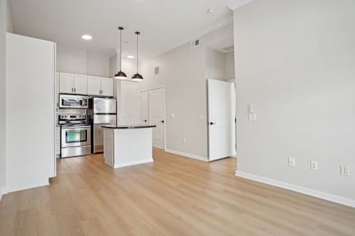 A kitchen with white cabinets and a wooden floor.