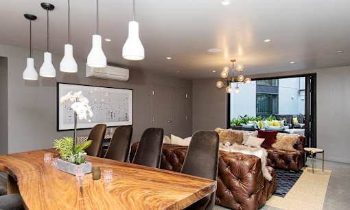 A modern dining room with a wooden table and brown leather chairs.