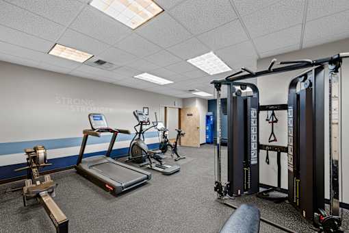A gym with a variety of equipment including a treadmill, weights, and a squat rack.