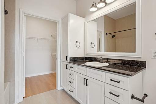 A bathroom with a sink, mirror, and cabinets.