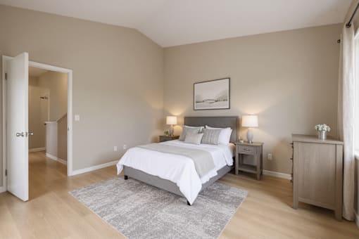 A bedroom with a large bed and a nightstand with a lamp.