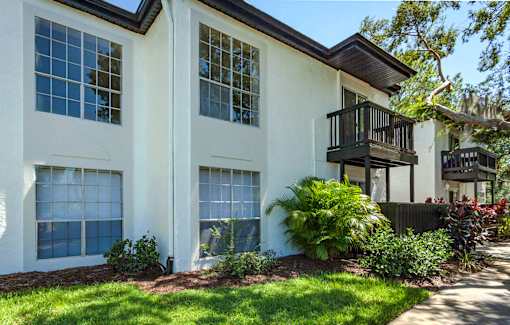 A white house with a balcony and a small garden in front.