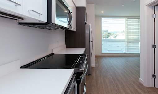 A modern kitchen with white countertops and black appliances.