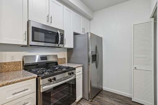 One-BR Apartments in Petaluma, CA - Theatre Square - Galley Kitchen With White Cabinets, Laminate Countertops, And Stainless-Steel Appliances Including Gas Range And Microwave.
