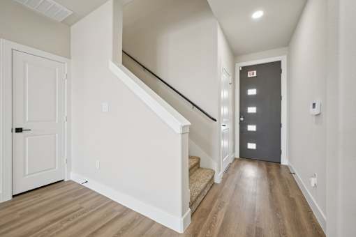 A hallway with a staircase and a white door.