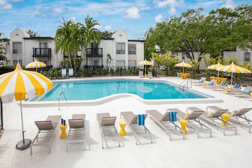 A pool surrounded by yellow umbrellas and lounge chairs.