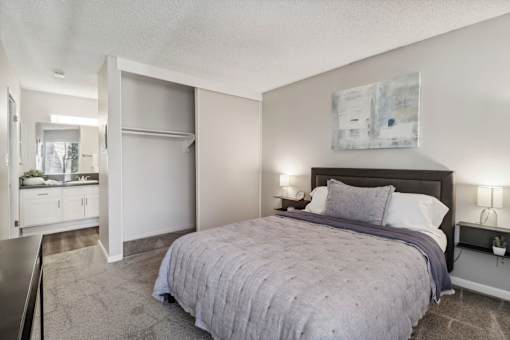A bedroom with a bed, nightstand, and a painting on the wall.
