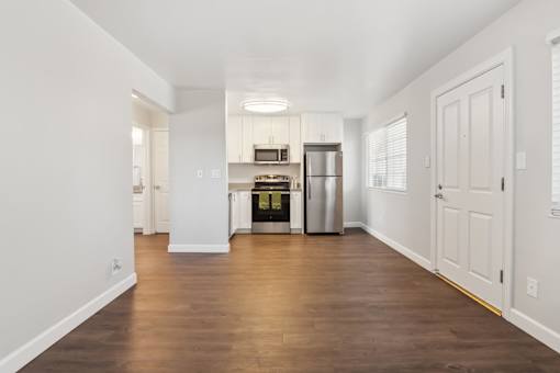 A kitchen with white cabinets and a wooden floor.