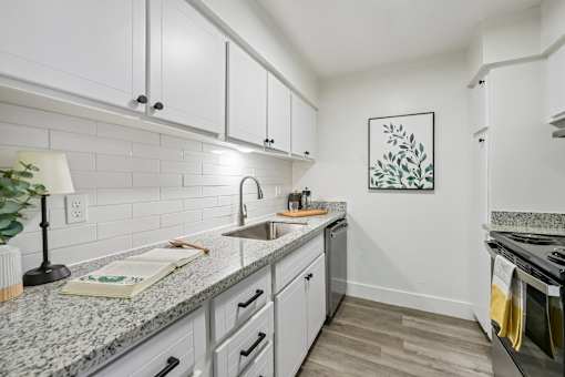 A kitchen with white cabinets and a granite countertop.
