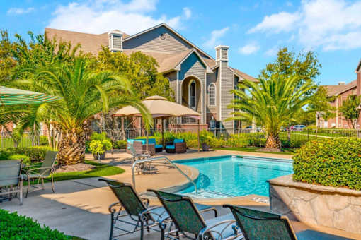 a swimming pool with chairs and umbrellas in front of a house