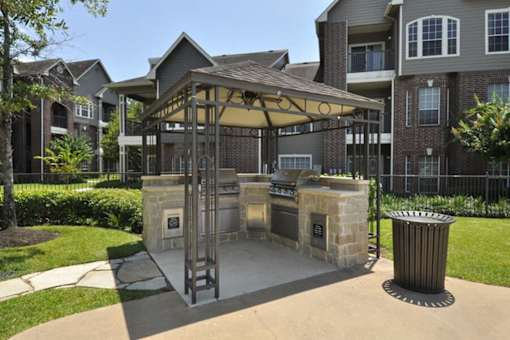 an outdoor kitchen with a gazebo in front of an apartment building