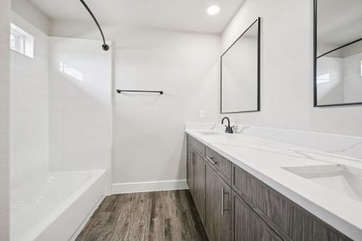 A modern bathroom with a white tub and wooden floors.