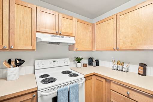 A kitchen with wooden cabinets and a white stove top oven.