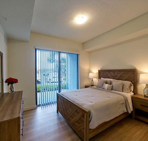 Spacious bedroom at Gateway Luxury Apartments in Pompano Beach, featuring large sliding glass doors that brings in abundant natural light.
