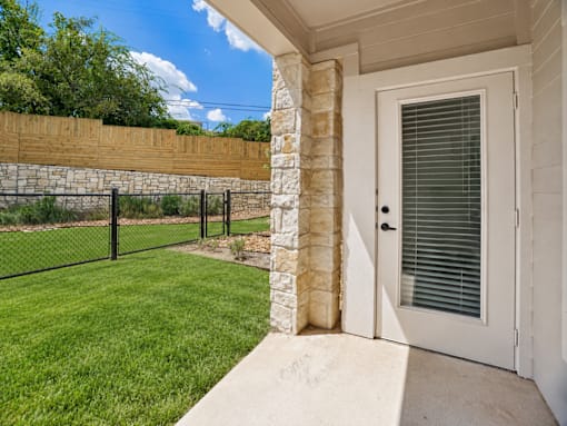 A white door with a window is on the right side of a concrete walkway.