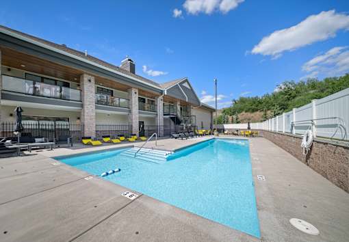 A large swimming pool in front of a building with a white fence on the right side.