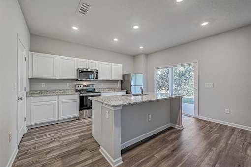 a kitchen with white cabinets and a large island with granite countertops