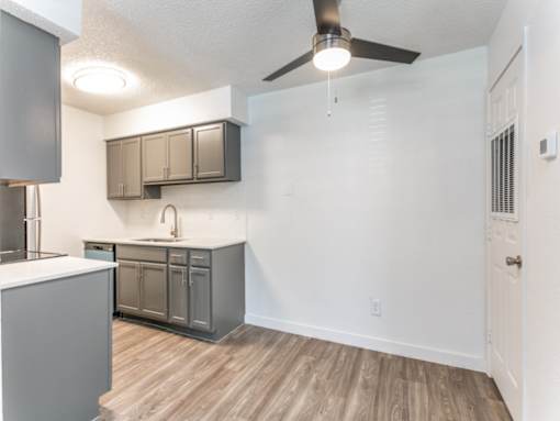 a kitchen and living room in an apartment with a ceiling fan