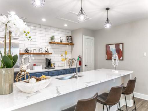 a kitchen with white countertops and a large white island with a sink and three chairs