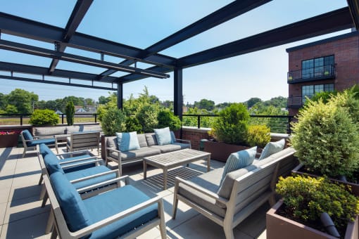 a roof terrace with couches and chairs and plants