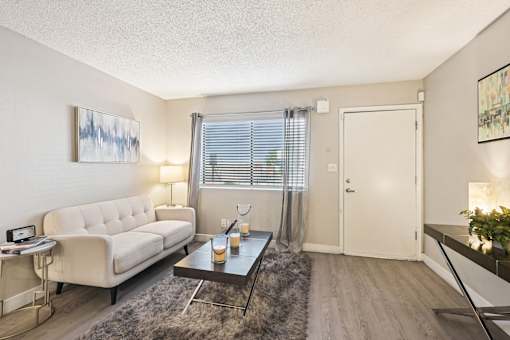 A living room with a white couch, a coffee table, and a painting on the wall.