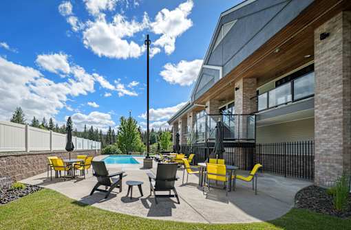 A modern outdoor patio with yellow chairs and a pool.