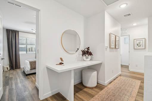 A white desk with a round mirror above it in a room.