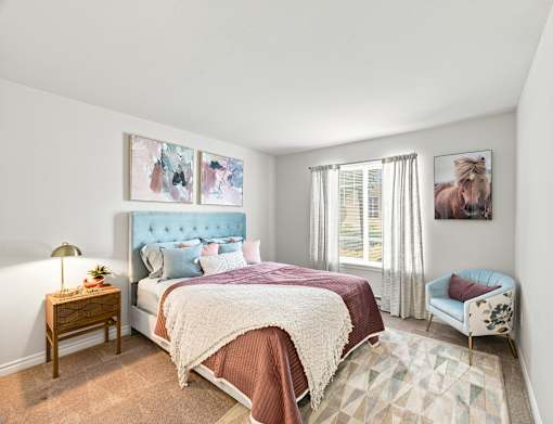 A bedroom with a large bed and a chair.