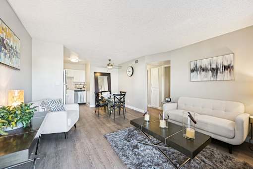 A modern living room with a glass coffee table and two white sofas.