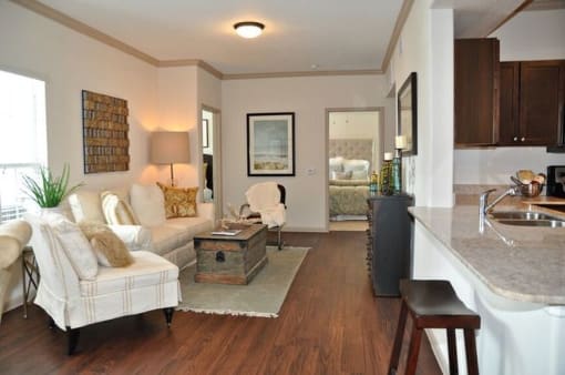 Living room with wood floors and couches and chairs and windows with blinds and ceiling light