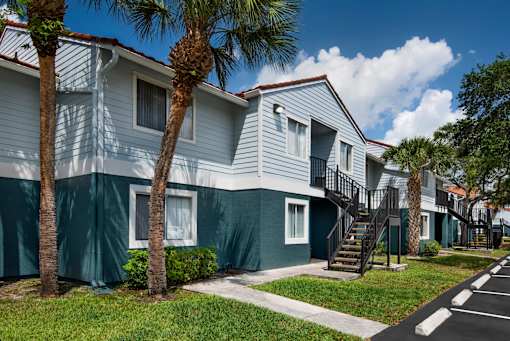 A row of houses with green trees in front.