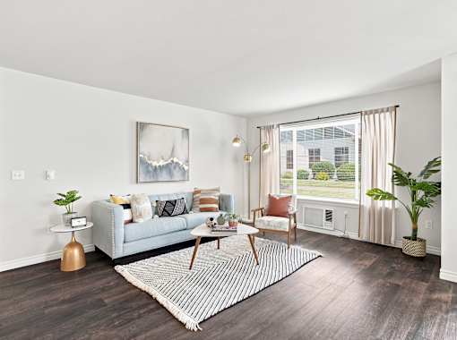 A living room with a grey couch, a coffee table, and a painting on the wall.