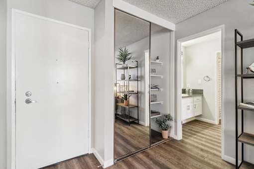A white door is open to a kitchen and living room.