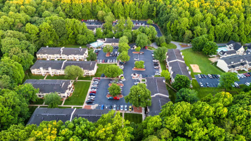 an aerial view of a parking lot with houses and trees