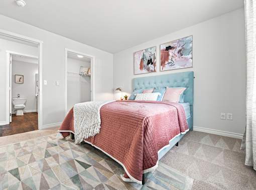 A bedroom with a bed covered in a pink blanket.