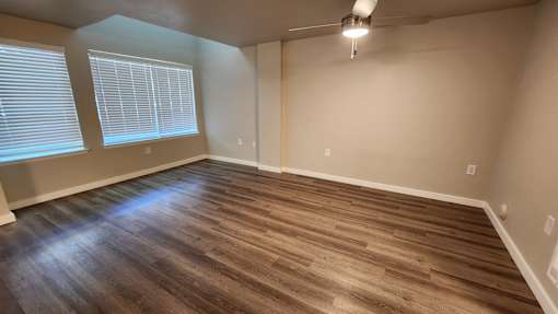 A room with wooden flooring and a window with blinds.