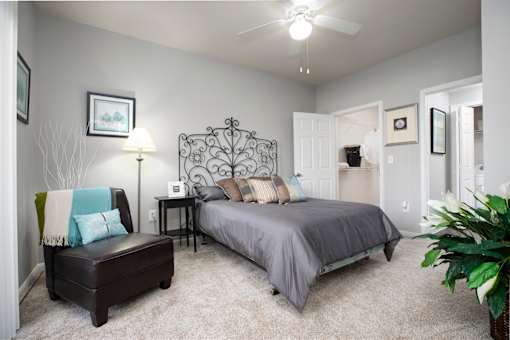 a bedroom with a bed and a chair and a ceiling fan