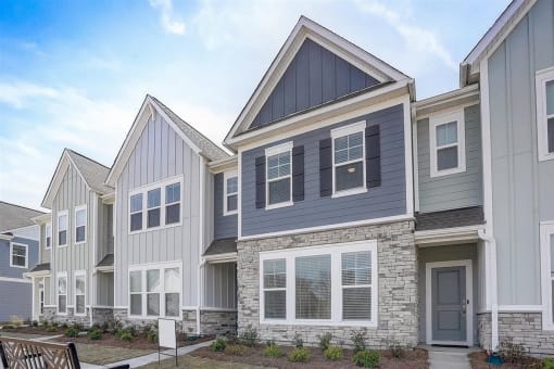 a row of townhomes with gray siding and a gray door