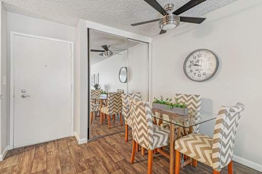A dining room with a glass table and chairs with a mirror above it.