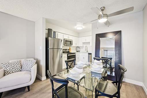 A modern kitchen with a glass dining table and chairs.